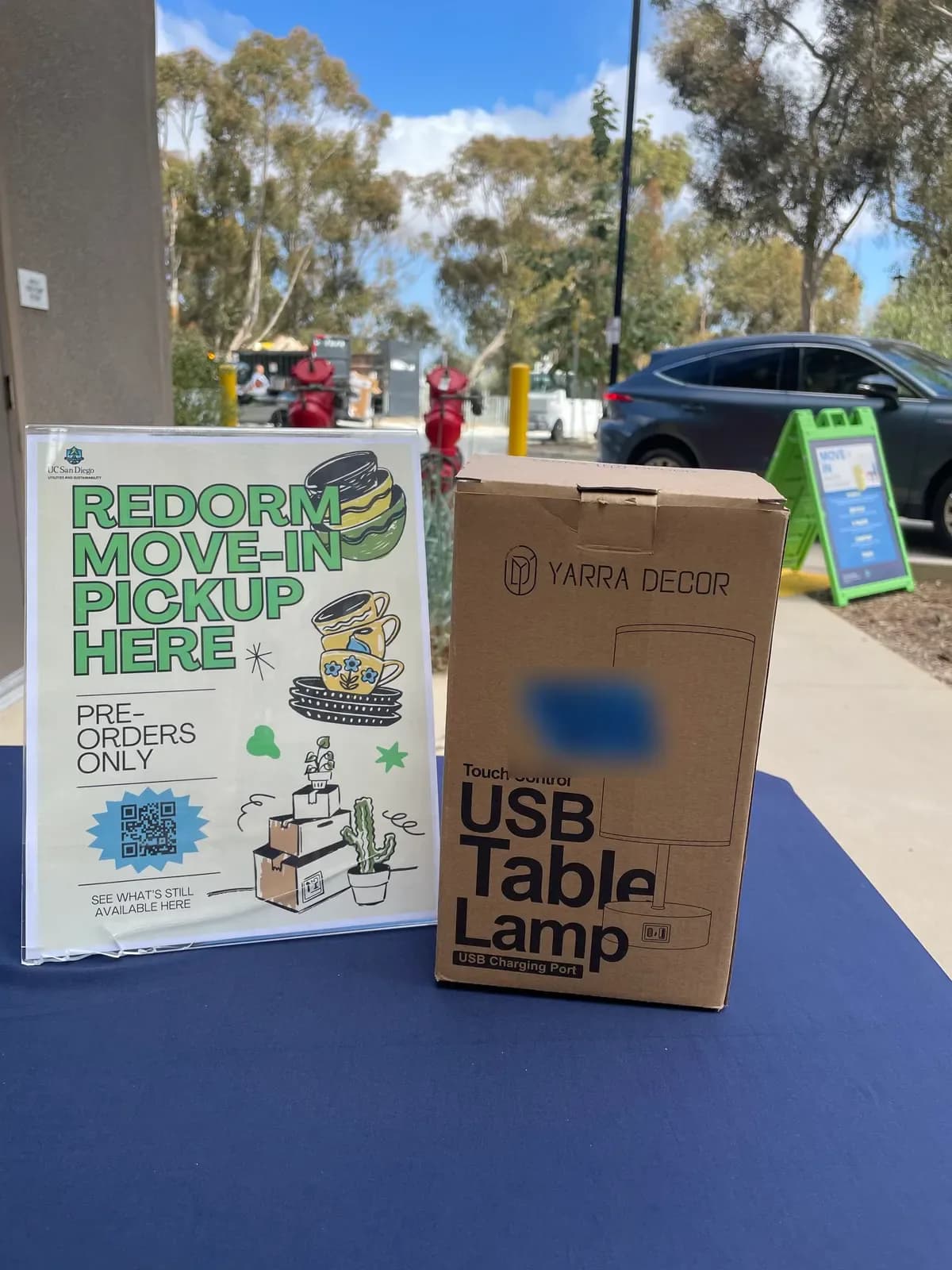 A ReDorm move-in pickup sign beside a boxed table lamp