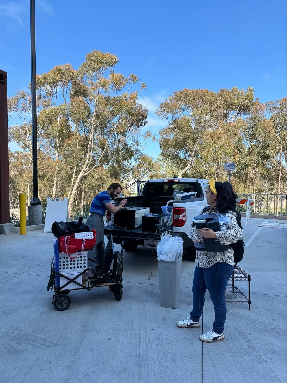 Two staff members loading microwaves and household goods from a cart into a pickup truck