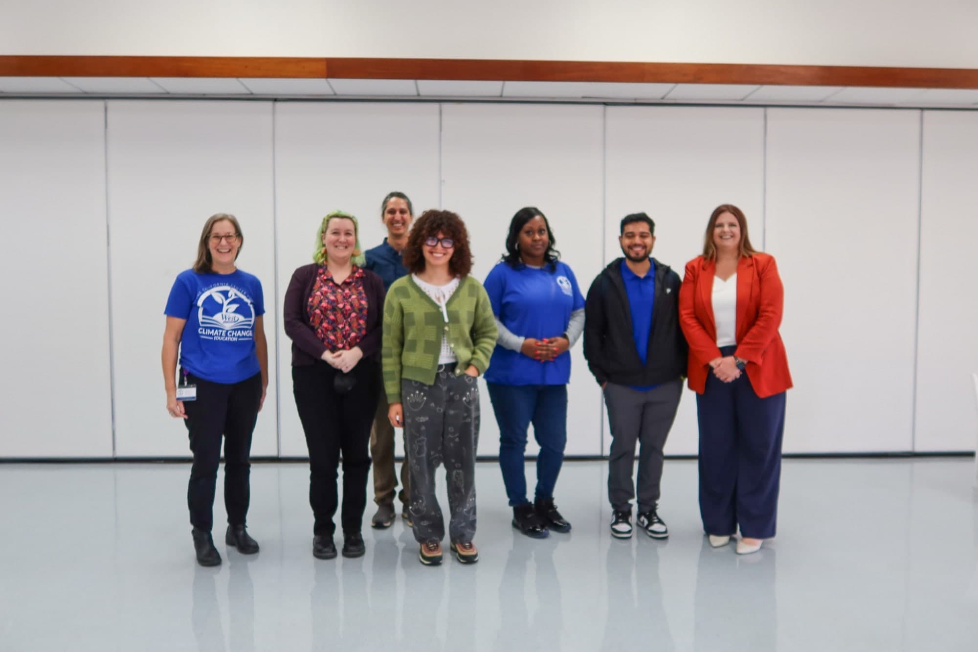 The seven panelists and hosts standing together indoors at West Los Angeles College after the final session, smiling at the camera