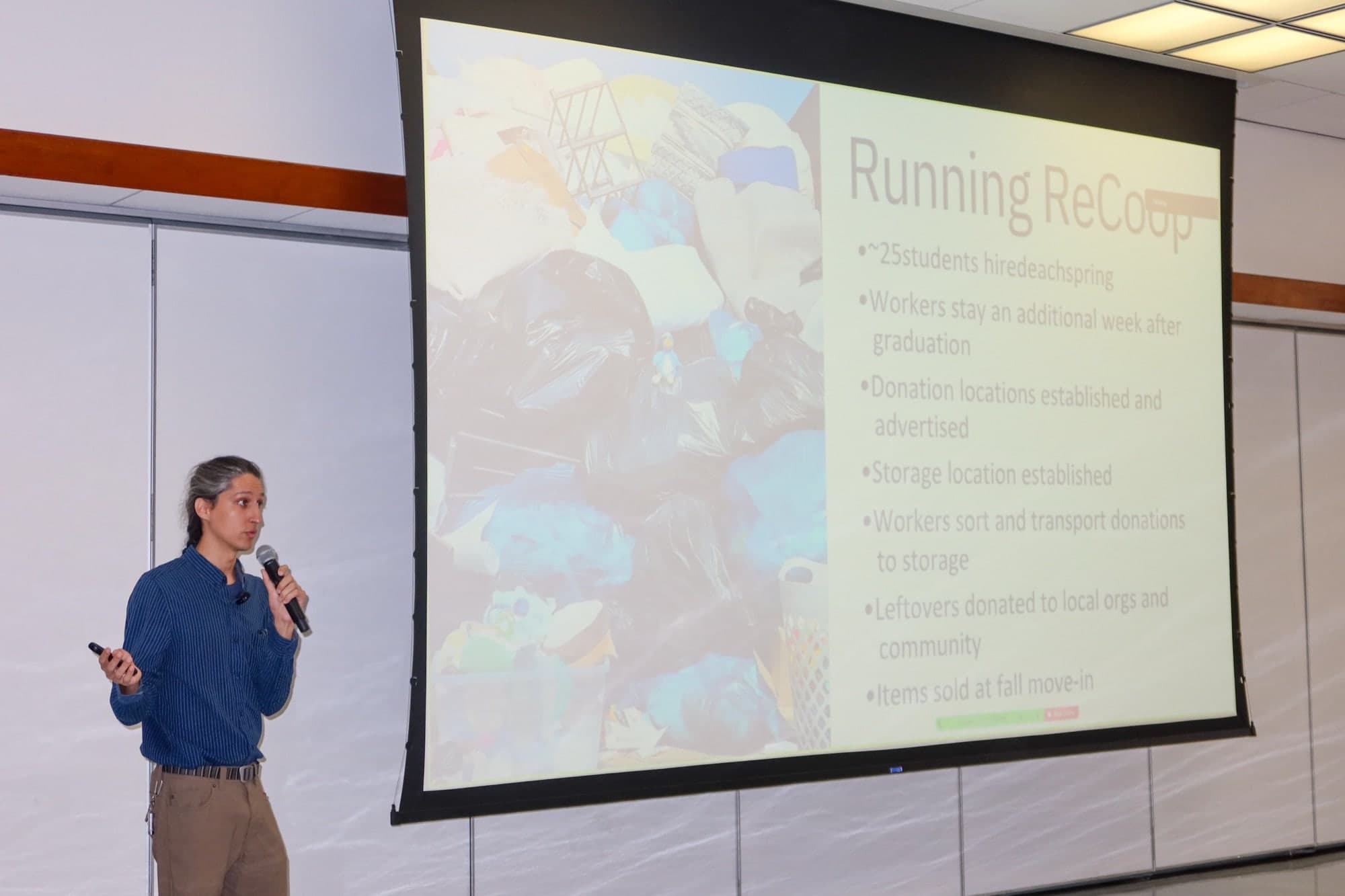 Nikhil Schneider holds a microphone beside a slide headed Running ReCoop, listing seven operational bullet points over a background photo of bagged donations