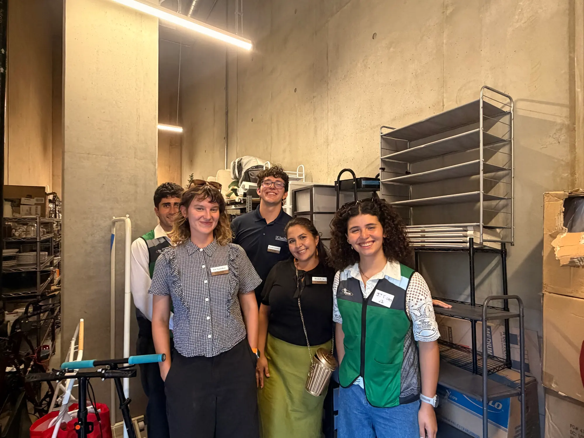 Five people from ReDorm and UC San Diego standing together in the concrete storage room where the campus collects everything students leave behind at move-out